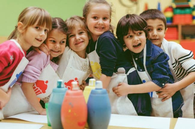 Portrait of Cute children painting with watercolors in a preschool.They are painting with watercolors on paper. They have some creative activities in a kindergarten. Standing in group, embracing and smiling. Studio Zuber. Spin Painting Leipzig. Kindergeburtstag in Leipzig feiern.